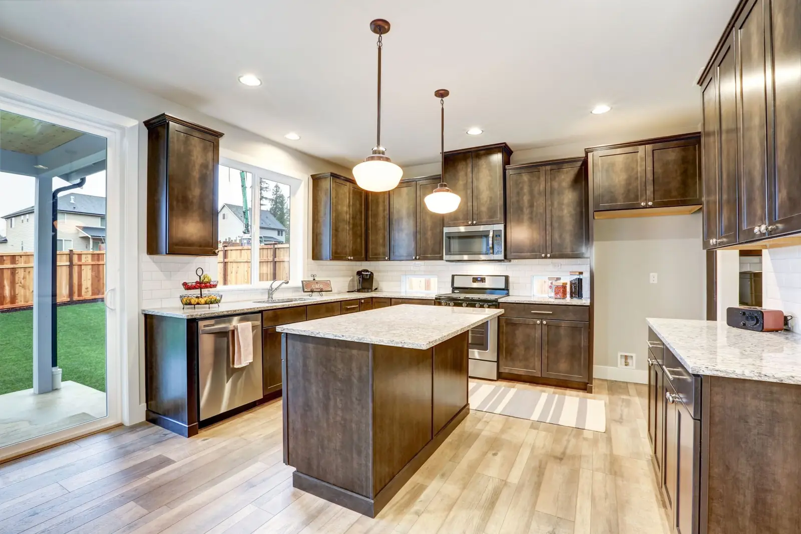 A finished kitchen with an island, pendant lights and wood cabinets