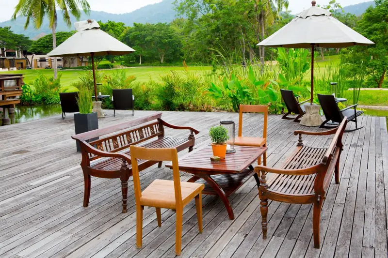 A wood deck with an outdoor dining set and umbrellas